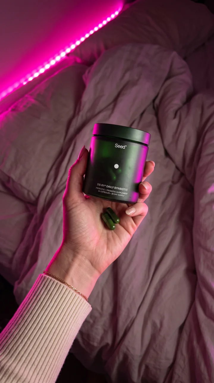 Night AI UGC ad still: Late-night LED hold. Magenta rim light in a dark bedroom.