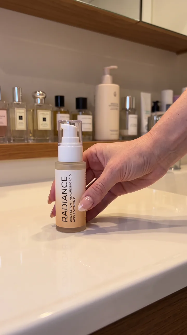 Bathroom AI UGC ad still: Bathroom vanity hold. Skincare shelf softly out of focus.