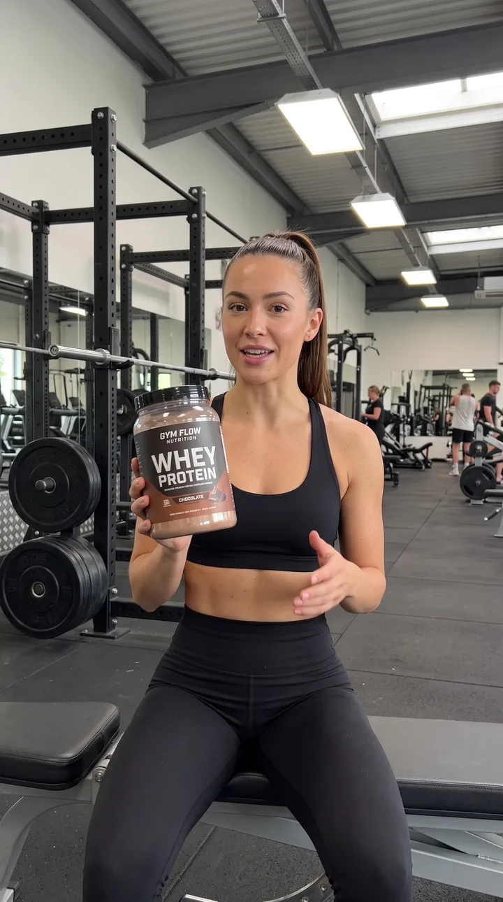 Fitness AI UGC ad still: Gym floor recommendation. Racks behind her, product to the lens.